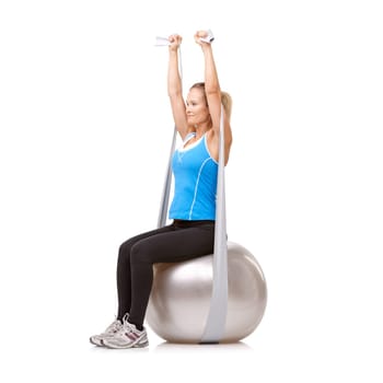 Yoga ball, resistance band and woman doing exercise in studio for health, wellness and body care. Sports, fitness and young female person from Canada with arms workout or training by white background.