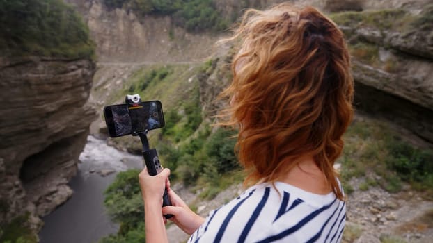 Woman taking video of beautiful gorge and river. Action. Concept of travelling