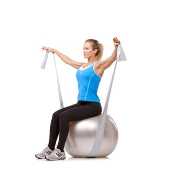 Yoga ball, resistance band and woman doing exercise in studio for health, wellness and body care. Sports, fitness and young female person from Canada with arms workout or training by white background.