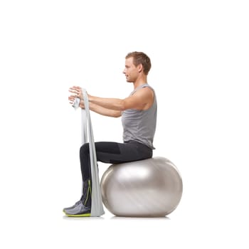 Yoga ball, resistance band and man doing workout in studio for health, wellness and bodycare. Sport, fitness and young male person from Australia with arms exercise or training by white background