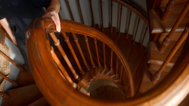 A twisted staircase made of wood. Action. A man in black clothes going up and down a rounded staircase. High quality 4k footage