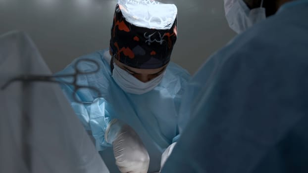 Professional doctors doing a surgery. Action. Close up of surgeon in sterile uniform at work, healthcare concept