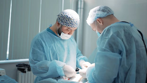 The concept of medicine . Action . Male surgeons in special special clothes, blue robes, gloves, masks who perform surgery on a special table. High quality 4k footage