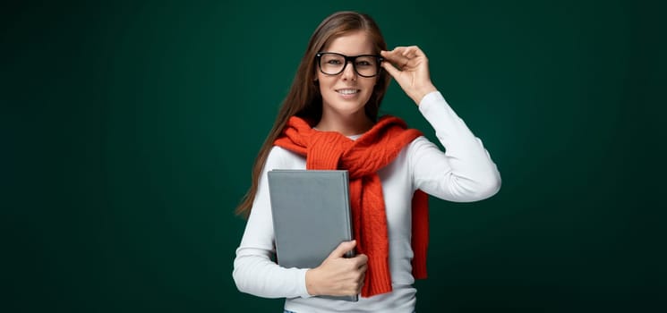 Smart young woman with brown hair holds a tablet in her hand.