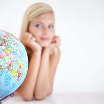 Globe, earth and a woman thinking about travel in studio on a blurry white background for freedom. Planet, map or atlas and a tourist with an idea for a holiday or vacation destination on the world.