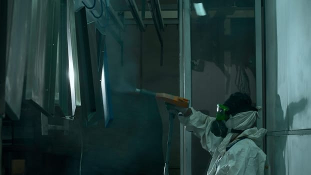 Male technician air-painting metal details at industrial plant. Creative. Industrial spray painting process