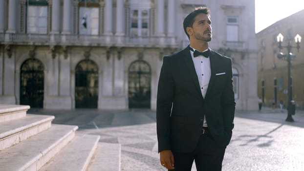 Elegant man in suit stands on street of European city. Action. Attractive man in elegant suit on sunny summer day. Man of dreams i suit.