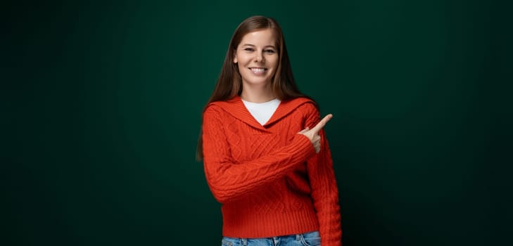 Attractive young woman dressed in a red sweater smiling on a green background.