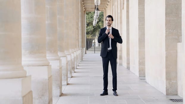 Young confident businessman in a formal suit by the columns of the buildings. Action. Elegant male portrait