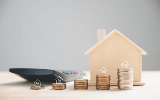 Hand stacks coins for property investment, a house as backdrop. Real estate growth, mortgage finance concept. Building wealth through wise investment is the goal. Property Taxes