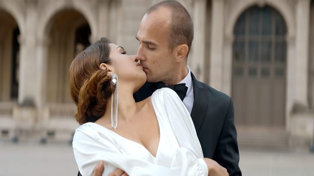 Loving couple video shooting on their wedding day. Action. Bride in white dress and groom in suit on the background of big city architecture