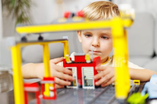 Child boy playing and building with colorful plastic bricks at the table. Early learning and development