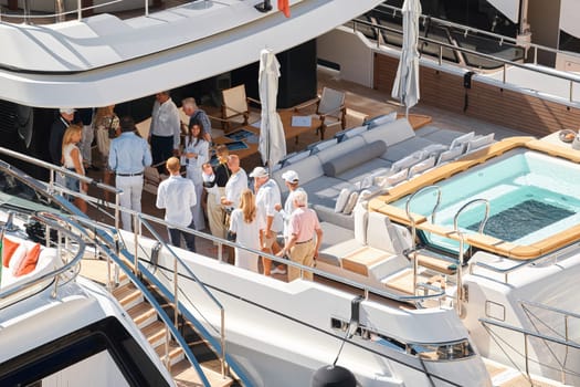 Monaco, Monte Carlo, 28 September 2022 - Invited wealthy clients inspect megayachts at the largest fair exhibition in the world yacht show MYS, port Hercules, yacht brokers, sunny weather. High quality photo