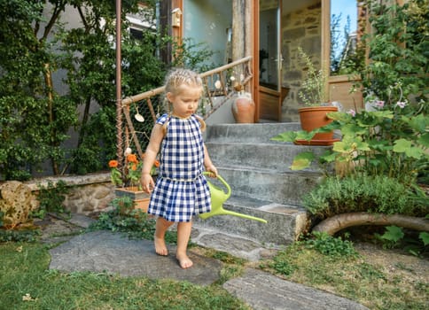 Little girl in a garden with green watering pot