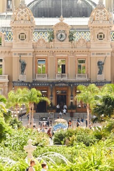 Monaco, Monte-Carlo, 28 September 2022 - Square Casino Monte-Carlo at sunny day, wealth life, tourists take pictures of the landmark, pine trees, blue sky. High quality photo