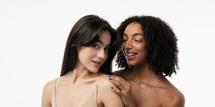 Female models of various ages celebrating their natural bodies in a studio. Two confident and joyful women smiling radiantly, having used cosmetics.