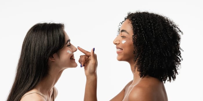 Female models of various ages celebrating their natural bodies in a studio. Two confident and joyful women smiling radiantly, having used cosmetics.