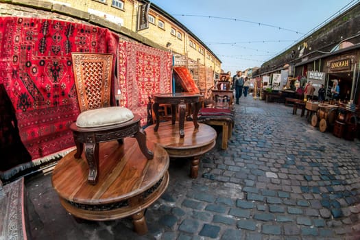 London, United Kingdom - April 01, 2007: Extreme wide angle (fisheye) photo of antique furniture chairs and carpets on display at Camden Lock, famous flea market in UK capital.