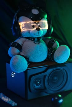 toy bear dressed in leather BDSM belts, headphones and glowing glasses in neon light listens to music. dark background