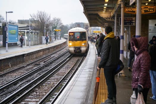 London, United Kingdom - February 01, 2019: Passengers waiting on station platform for National rail train at Lewisham during rainy overcast day