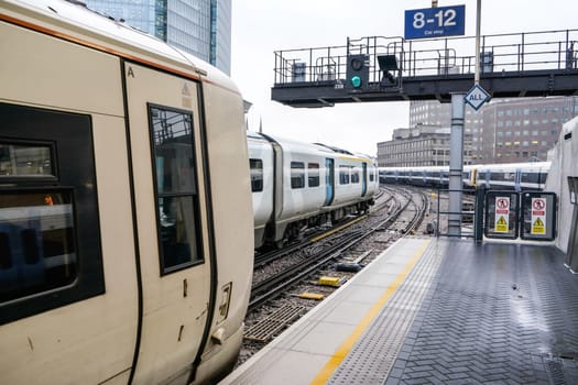 London, United Kingdom - February 01, 2019: Empty platform at London Bridge station, multiple trains on rail tracks, tall buildings background during overcast day