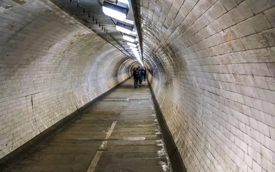 Wide angle photo of Greenwich foot tunnel under river Thames in London, blurred pedestrians in distance