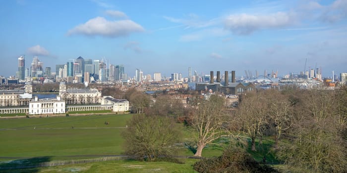 London, United Kingdom - February 02, 2019: Panorama of east London as seen from Greenwich. Skyscrapers at Canary Wharf, National Maritime museum and O2 Arena visible, on sunny spring day