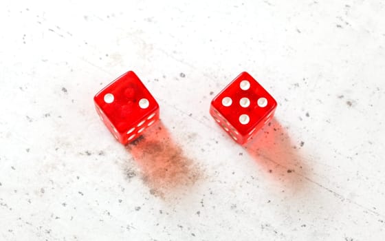 Two red craps dices showing Natural or Seven Out (number two and five) overhead shot on white board