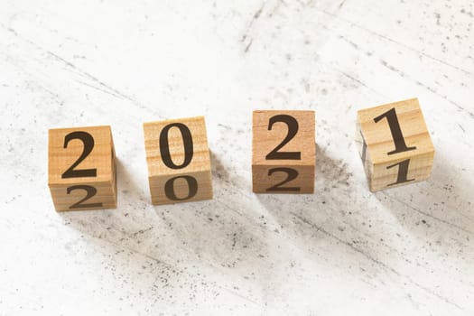 Four wooden cubes with number 2021 (new year) on white working board.