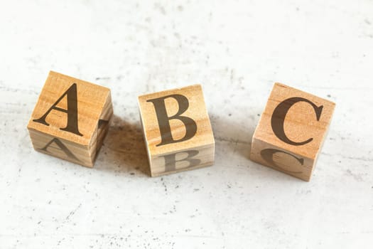 Three wooden cubes with letters ABC - stands for Always Be Closing - on white board.