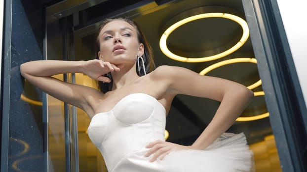Elegant bride in dress posing. Action. Stylish bride in white dress poses against modern background. Modern elegant bride at photo shoot.