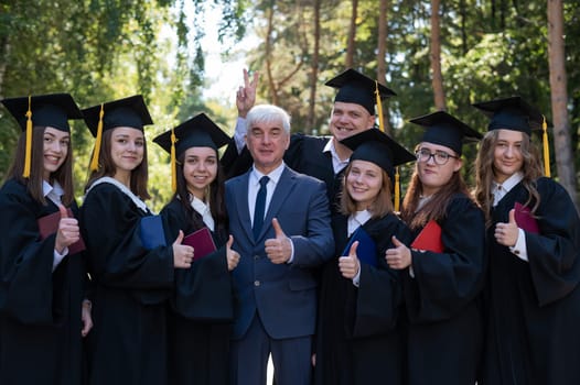 University professor and seven students rejoice at graduation and show thumbs up outdoors