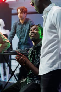 African american friends chatting while clubbing together in nightclub. Young men talking while resting near stage in club, relaxing at party and enjoying nightlife leisure activity