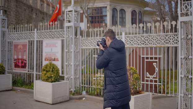 Photographer shoots architecture on camera. Action. Professional male photographer walks around city and shoots landscapes. Man walks around city with professional camera.