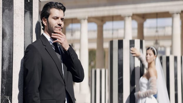 Newlyweds, caucasian bride and groom posing by the building outdoors. Action. Woman in white dress with a man in suit