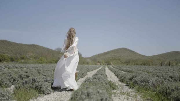 Woman posing in a field. Action.Cute blonde model with long hair posing in the wind with a hat in her hands. High quality 4k footage