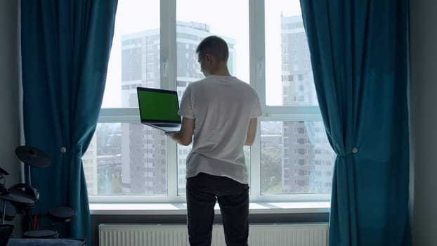 The screen in the laptop is green. Media. A man picking at a laptop with a green screen in front of a light window