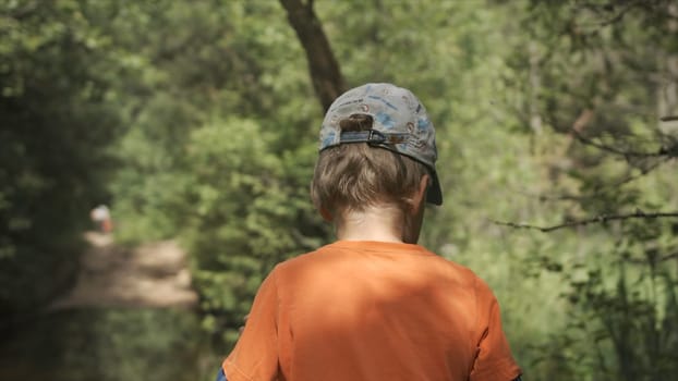 Boy walks through summer forest. Creative. Boy walks alone on forest trails on sunny day. Walking in summer forest.