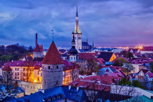 Aerial view of Tallinn Medieval Old Town with St. Olaf's Church and Tallinn City Wall illuminated in evening, Estonia