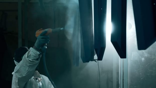 Worker at a factory moving a line of metal sheets. Creative. Man in suit using a steel stick to push the pipe with sheets