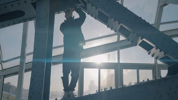 Young man dances on bridge on background of sun. Action. Young man is dancing on modern building structure.