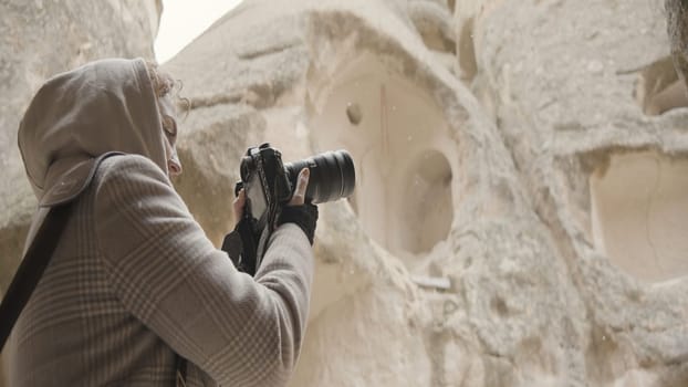 Beautiful woman takes pictures on trip with professional camera. Action. Female photographer takes pictures on camera while traveling. Attractive woman with camera for professional photos.