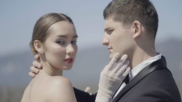 Sensual man and woman showing tenderness towards each other. Action. Portrait of sexy couple expressing feelings outdoors, a woman in gloves and a man in suit