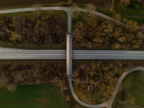 Light trails of cars driving under a pedestrian bridge, top down aerial.