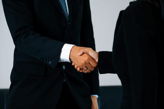 Business people agreement concept. Businessman and Asian businesswoman do handshake in the office. uds