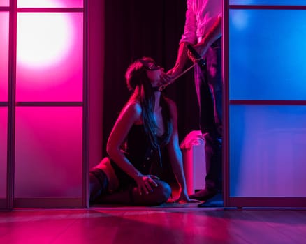 A woman is kneeling in front of a man. BDSM sex concept. Vertical photo