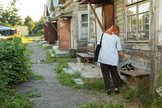 Girl at old house. Student came to poor house. Girl looking for address in ghetto. Details of walk in summer. Poor district.