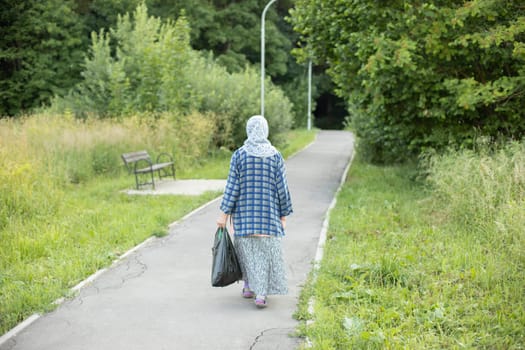 Woman with bag walks through park. Girl in park. Man on street. Walking along road. Woman in Russia on street.