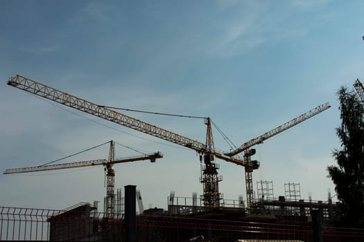 Construction crane against sky. Construction site view. Industrial construction. High-altitude equipment. Construction of structure.