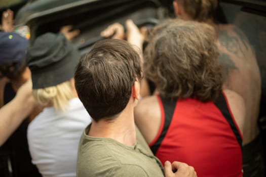 People load things into car. Guy holds heavy load. Tourists load transport. Movers in action.